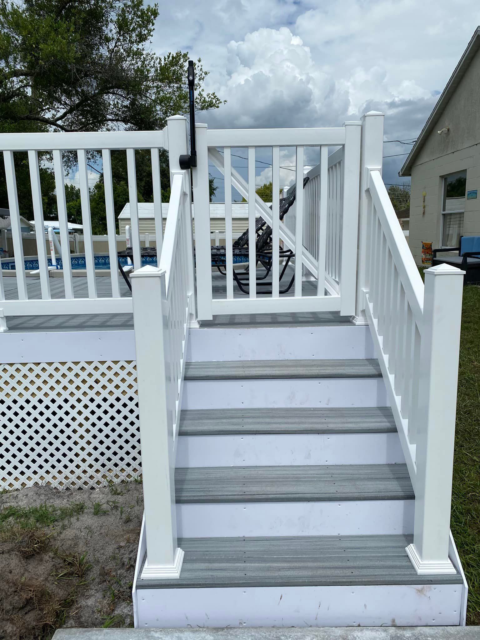 A white deck with stairs leading up to it and a gate.