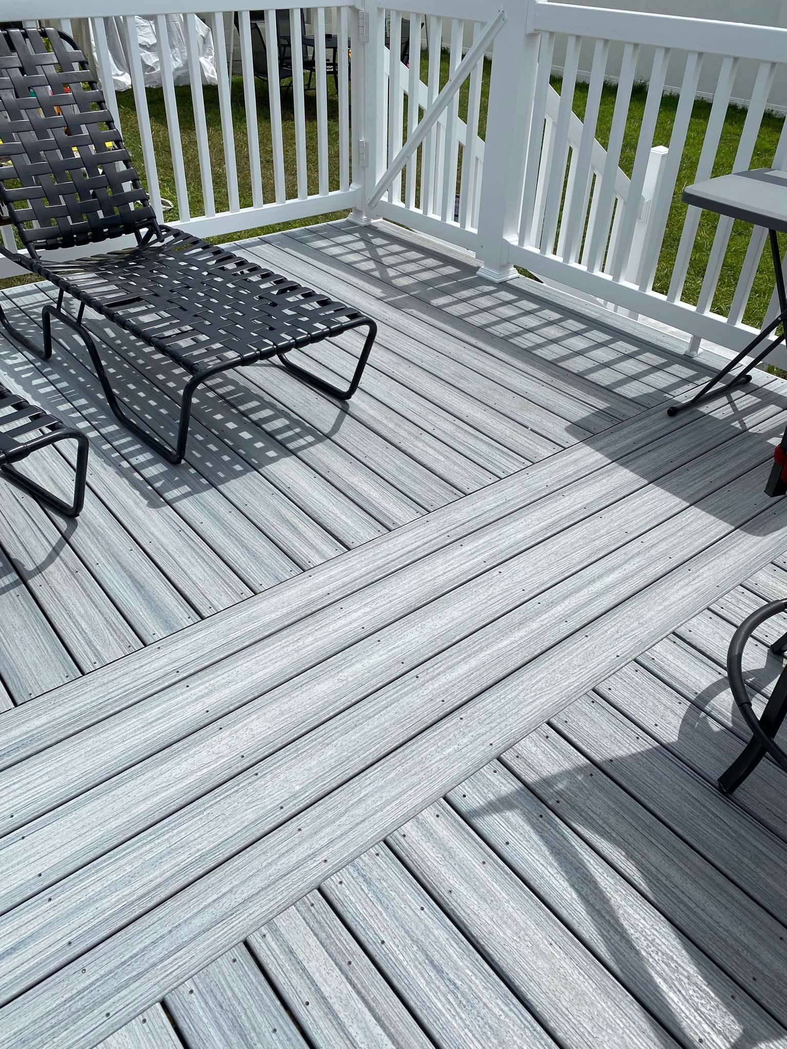 A white deck with chairs and a white railing.