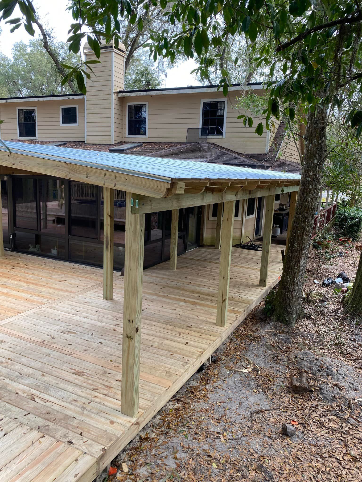 A wooden deck with a screened in porch in front of a house.