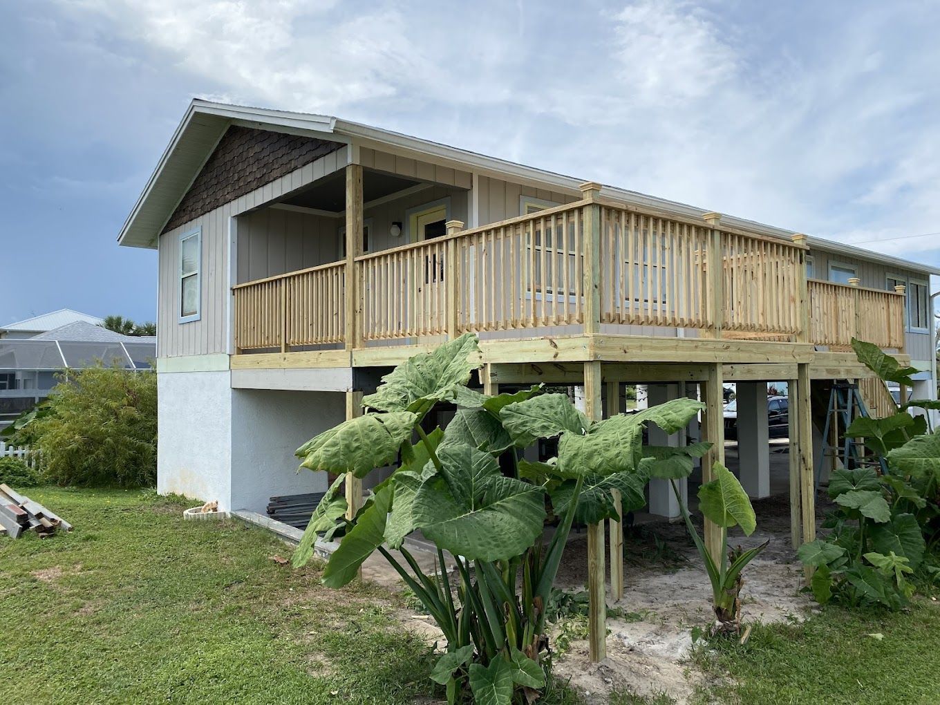 A house with a wooden deck is sitting on top of a lush green field.