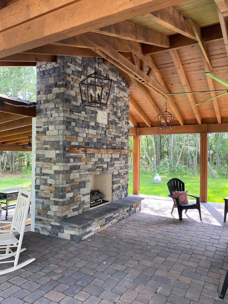 There is a large stone fireplace in the middle of the patio.