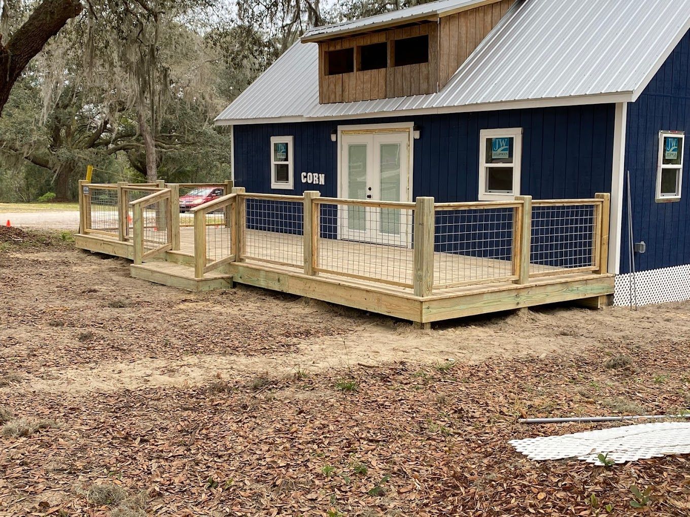 A blue house with a wooden deck in front of it.