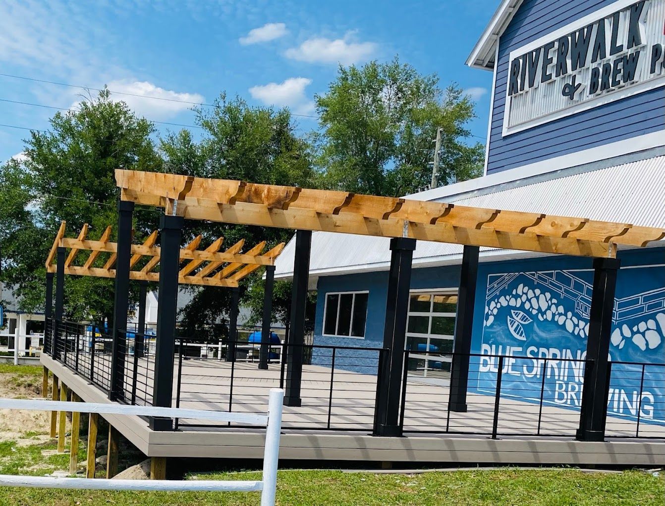 A blue building with a wooden pergola on the side of it.