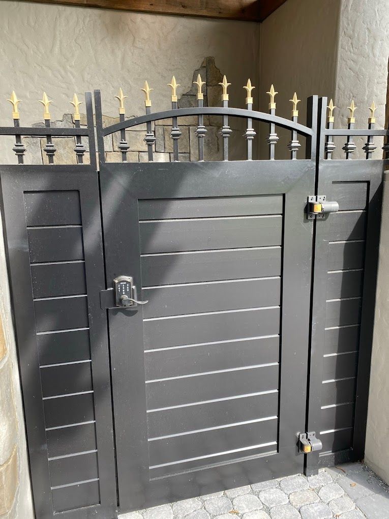 A black gate with gold spikes is sitting next to a wall.