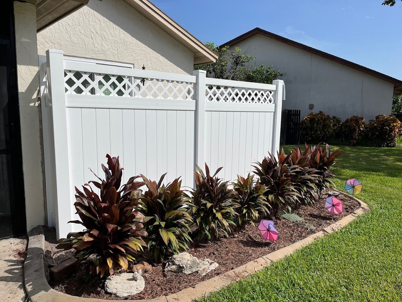A white fence is surrounded by plants and flowers in a yard.