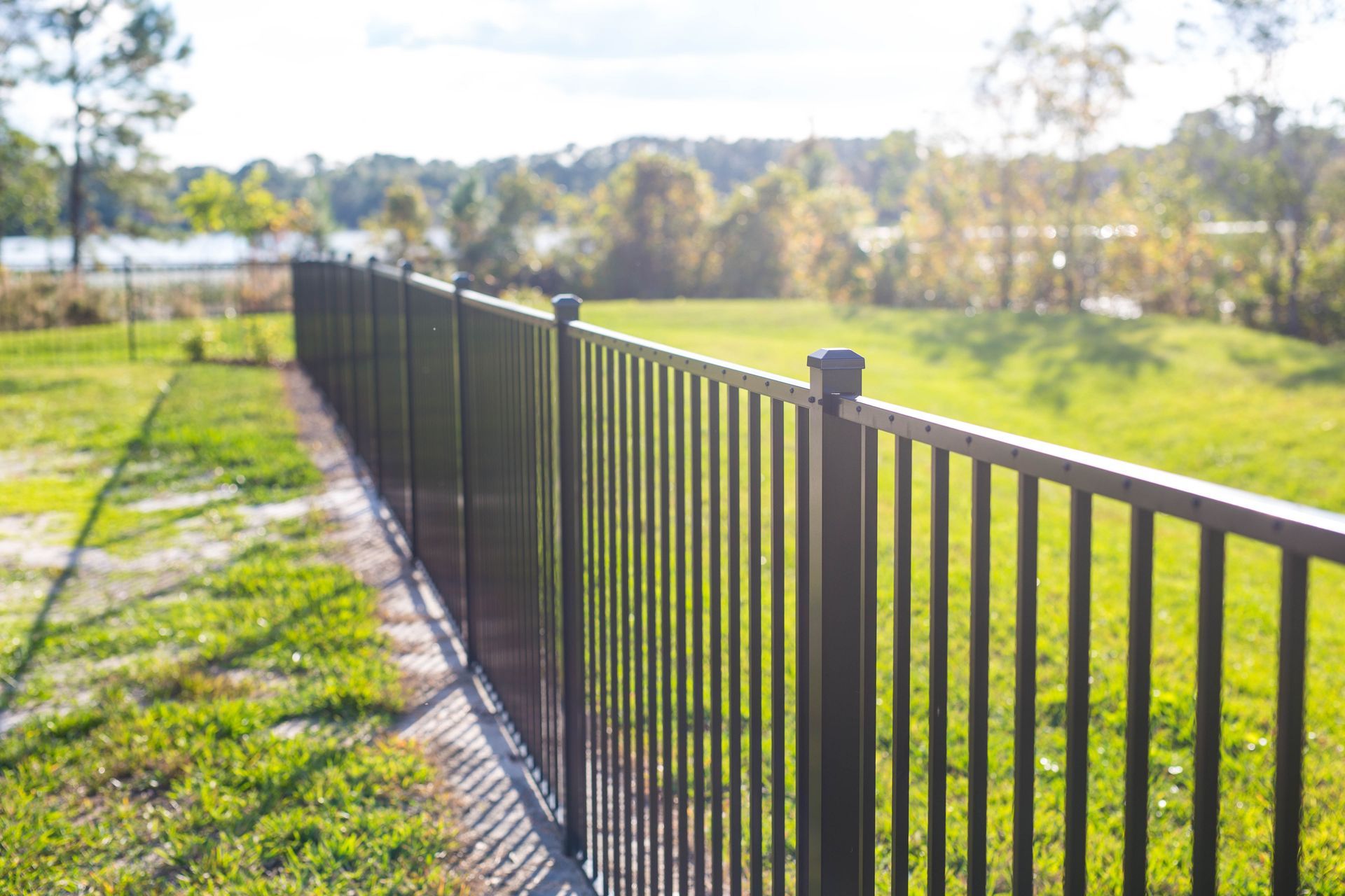A black metal fence surrounds a lush green field.
