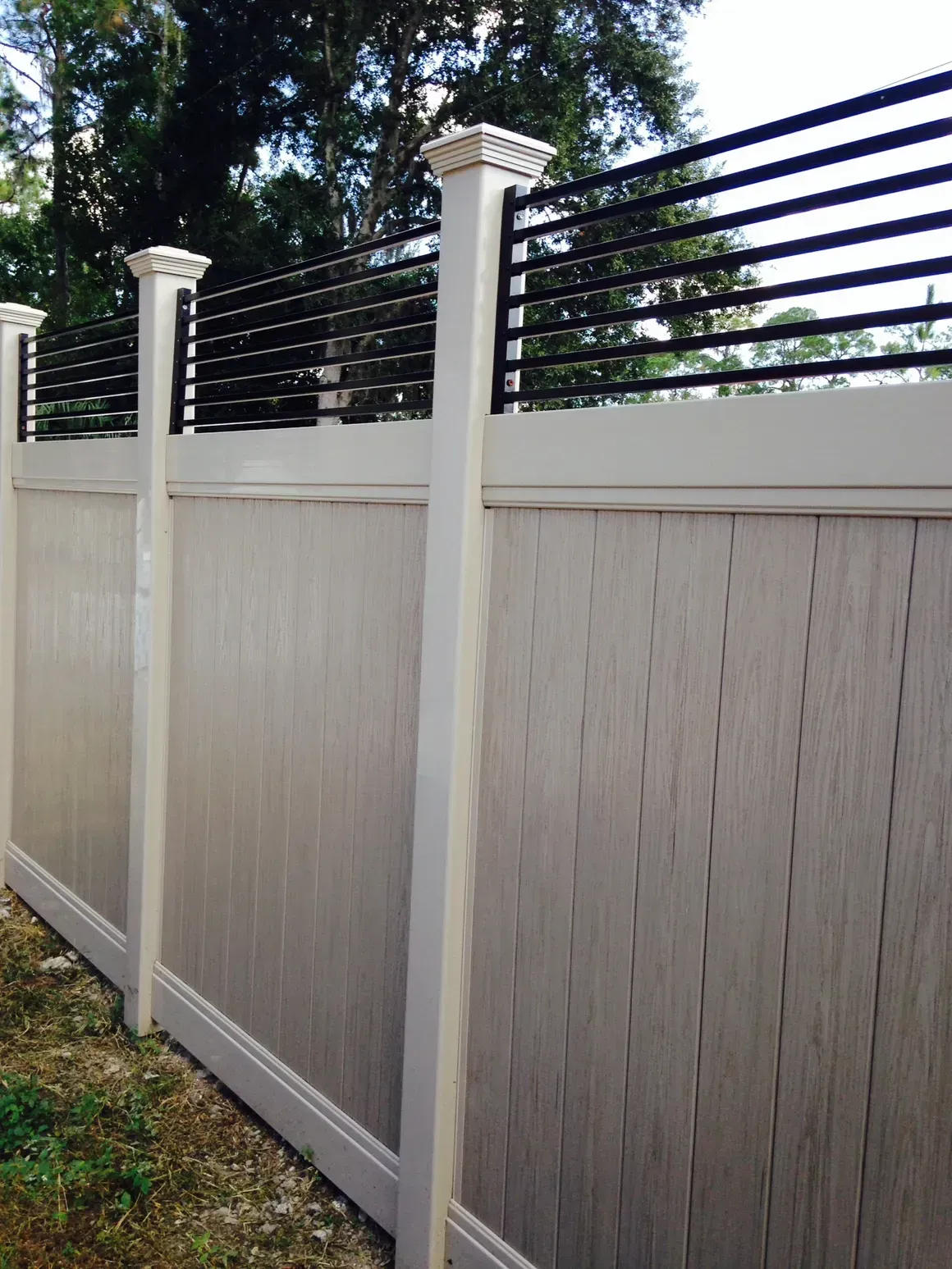 A white fence with a black railing on top of it.
