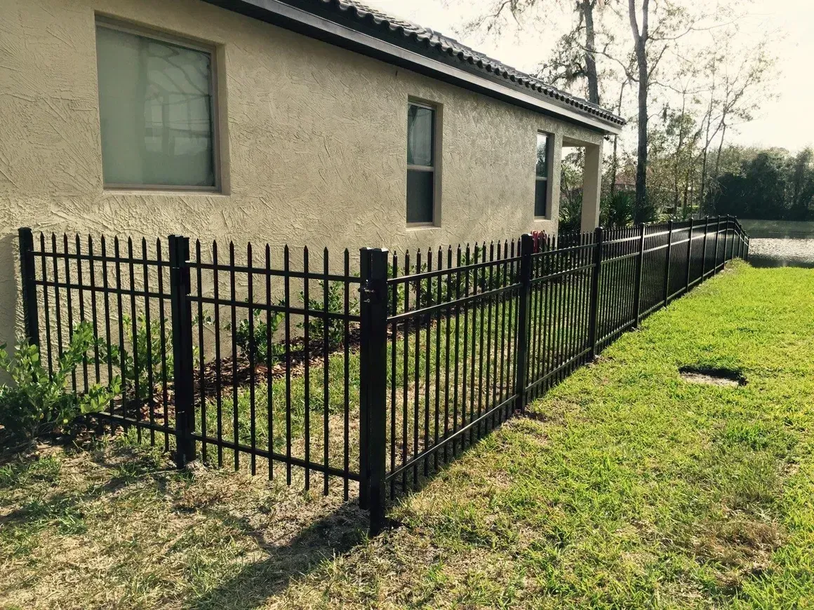 A black metal fence is in front of a house.