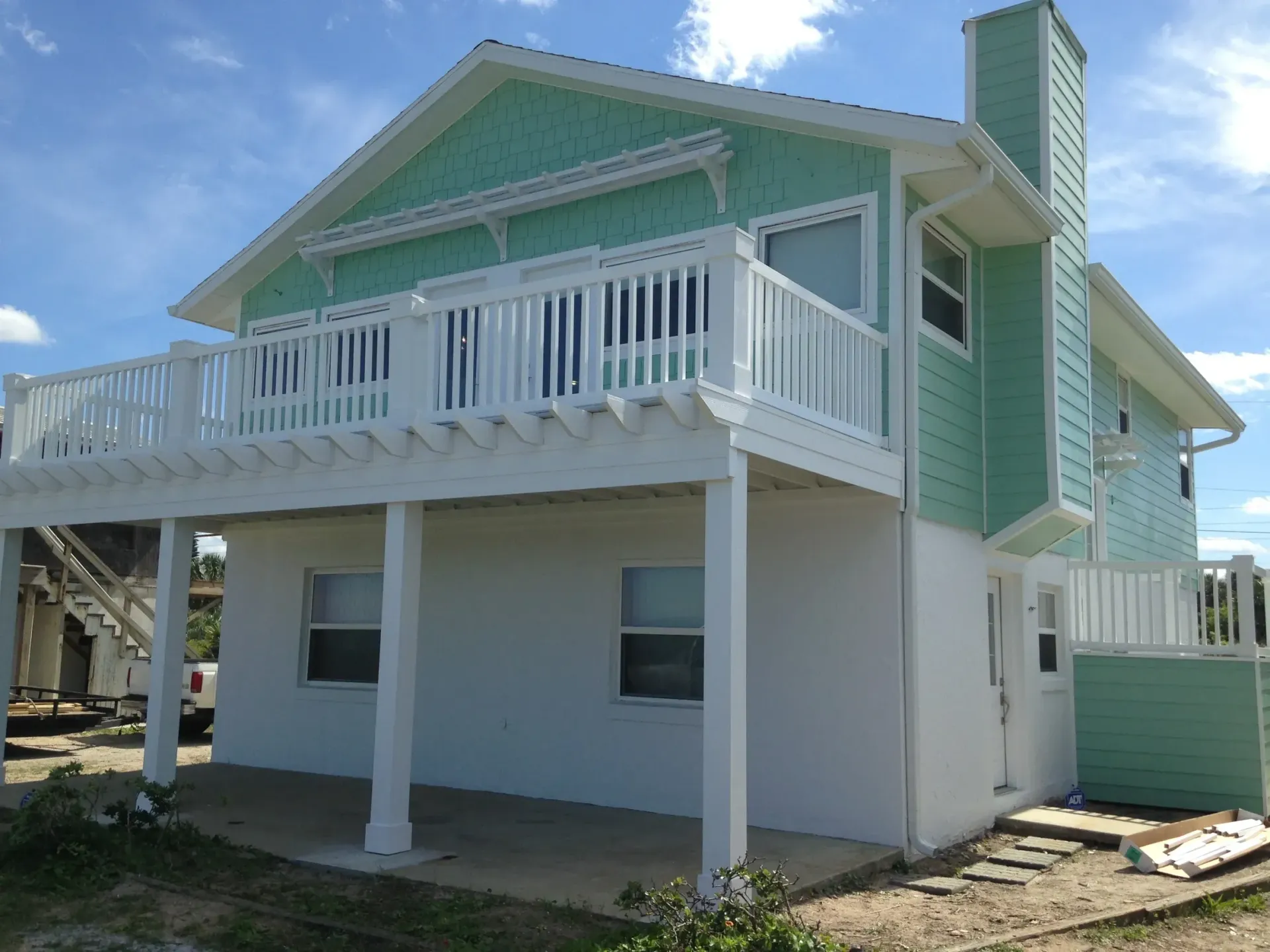 A green and white house with a large balcony