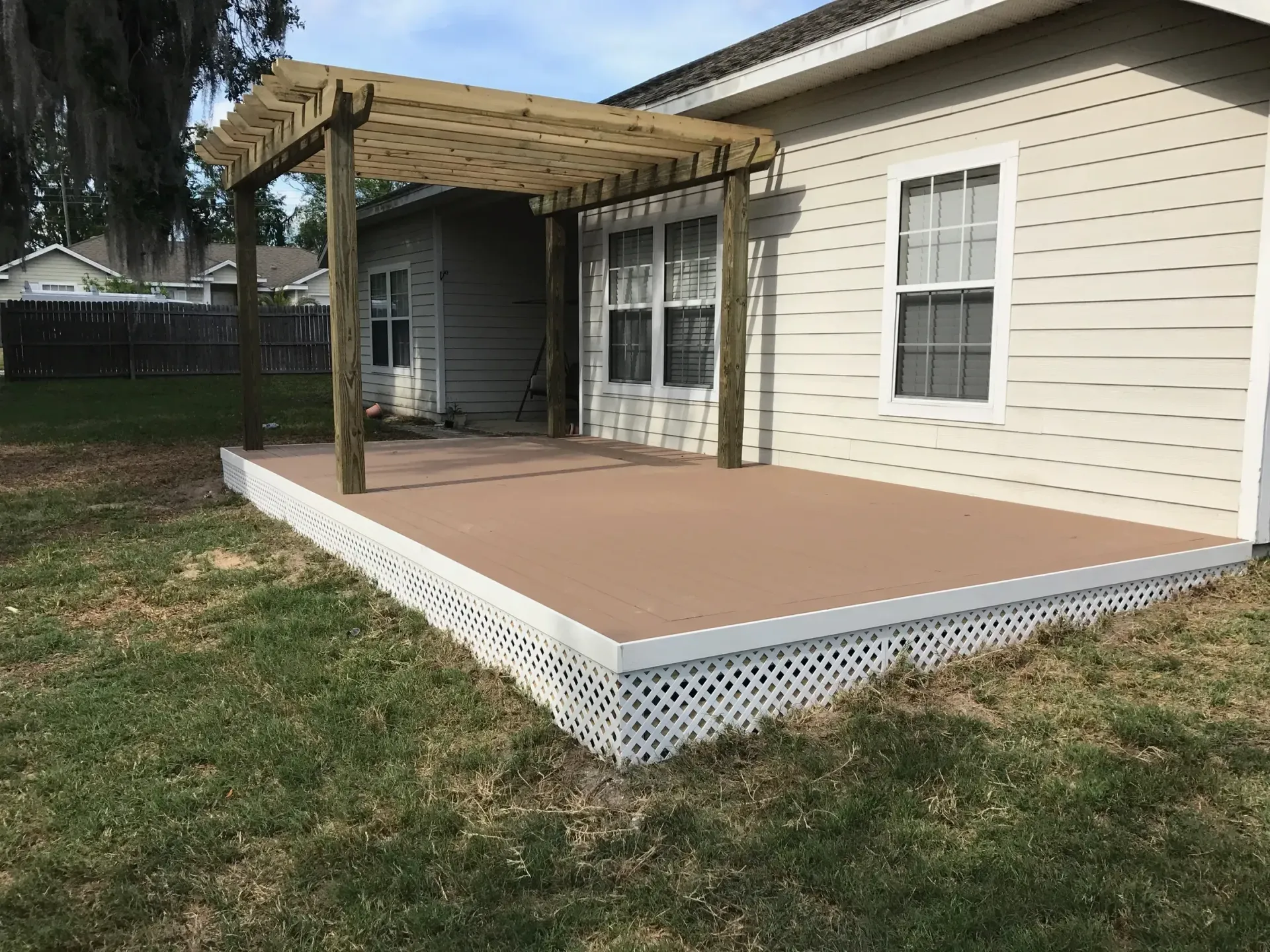 A house with a deck and a pergola in the backyard.