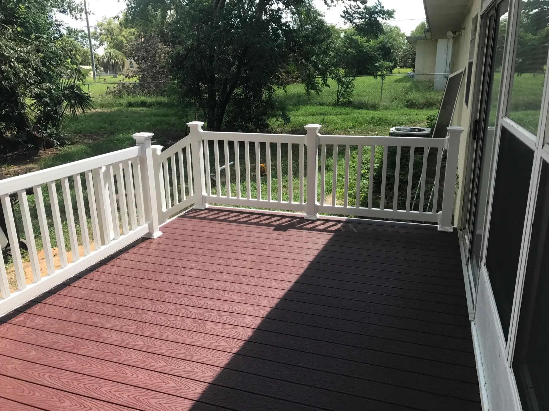 A porch with a white railing and a red floor.