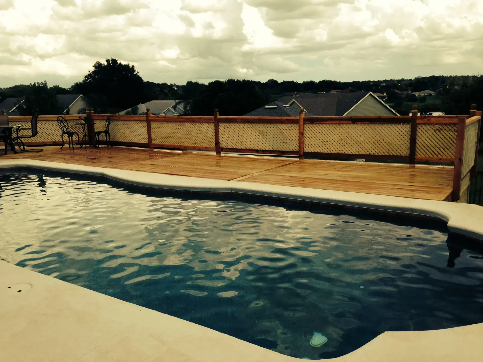A large swimming pool with a wooden deck surrounding it