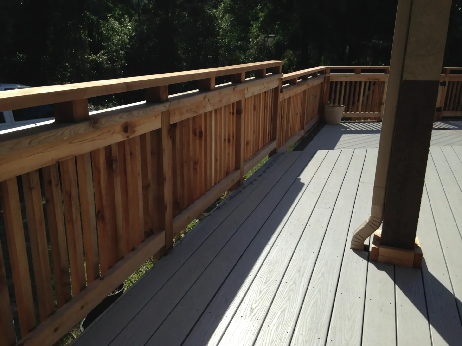 A deck with a wooden railing and a gray floor