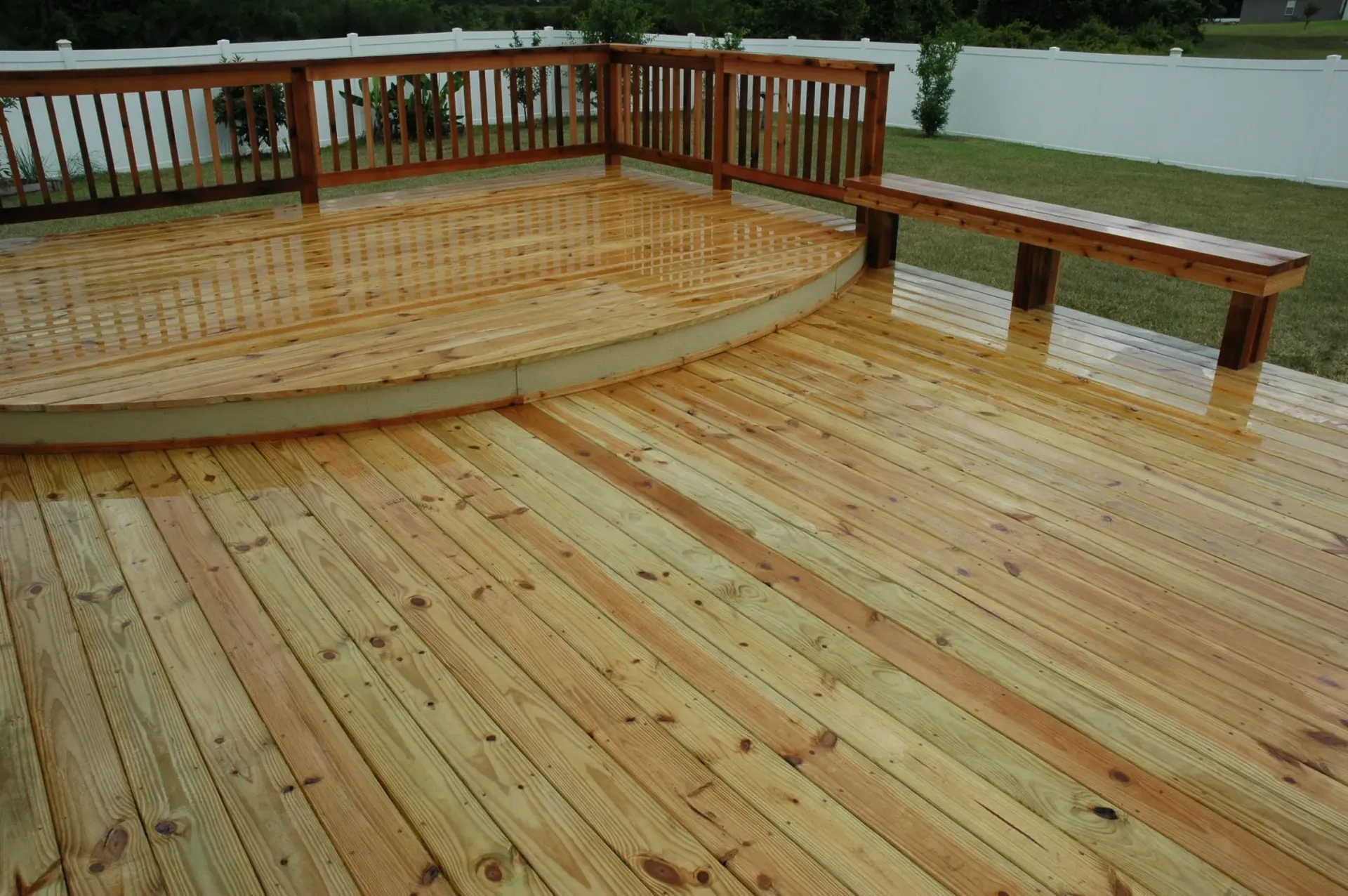 A wooden deck with a bench and a railing.