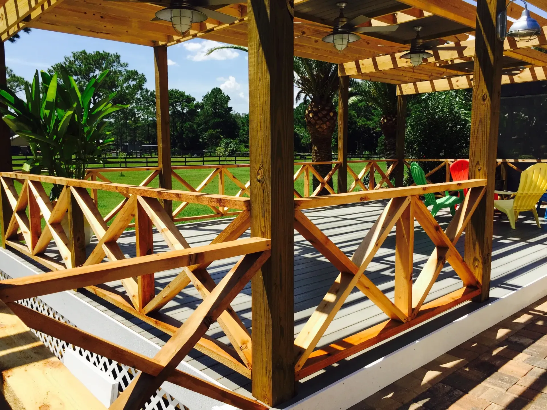 A wooden gazebo with chairs and a ceiling fan