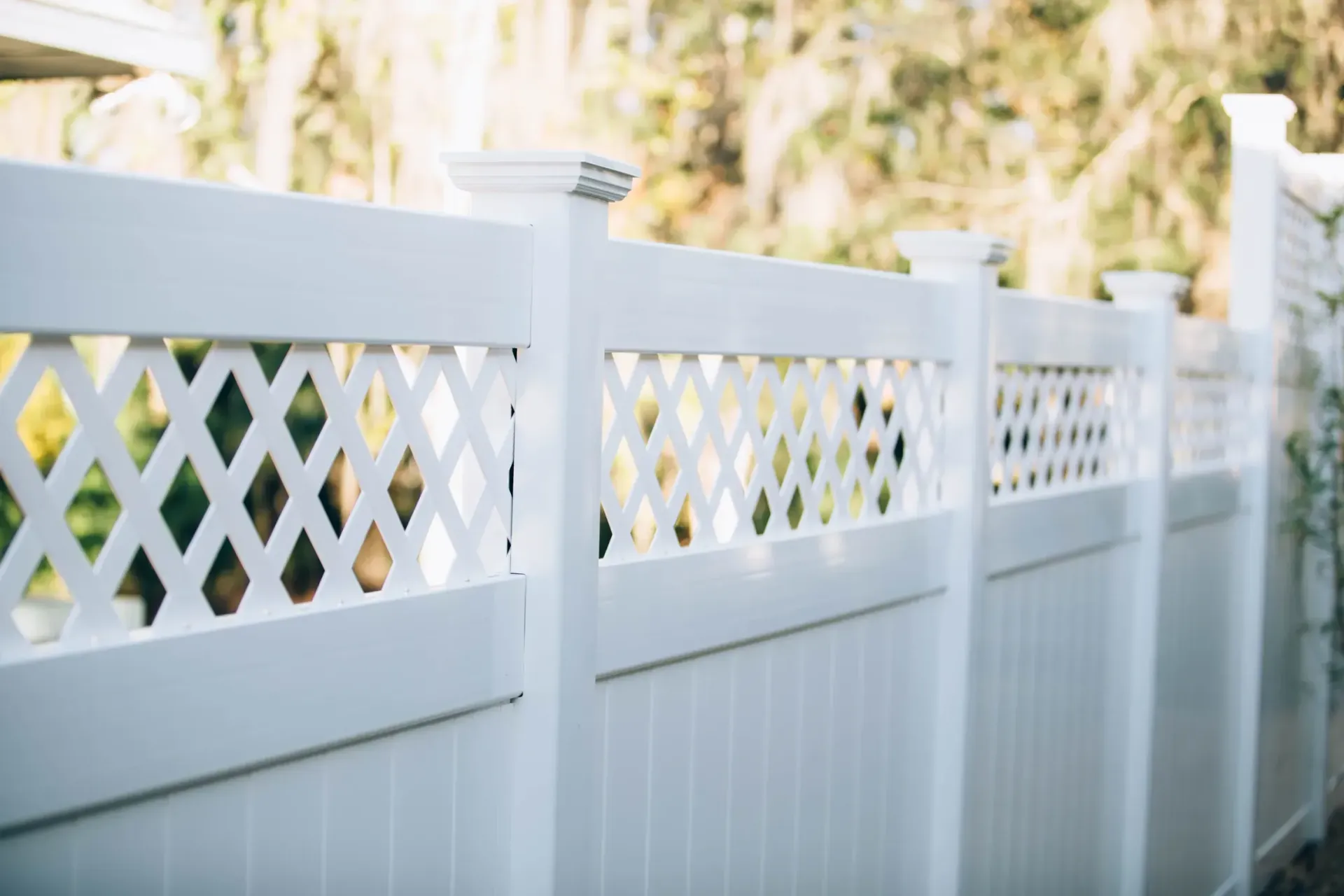 A close up of a white vinyl fence with a lattice design.