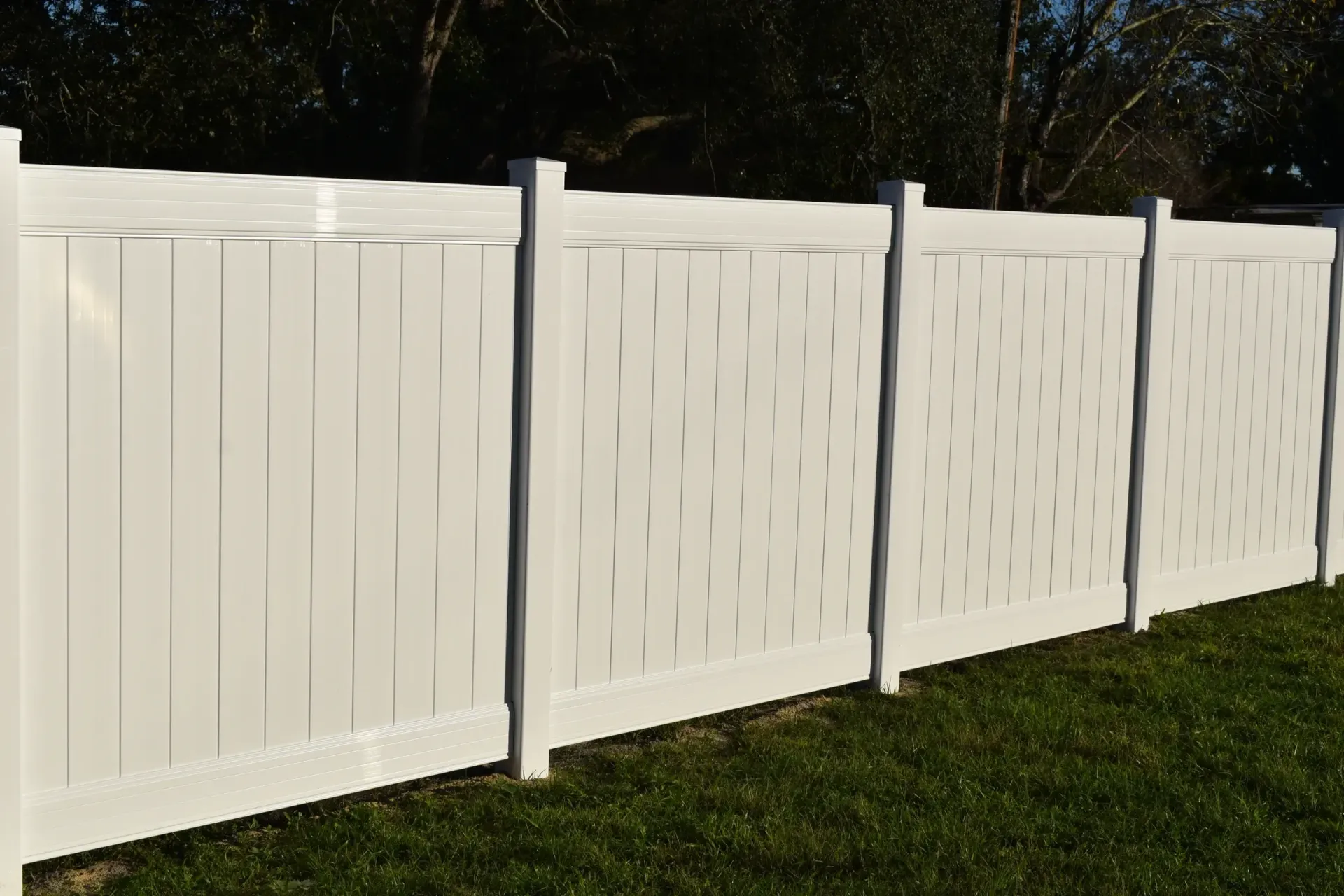 A white fence is sitting in the middle of a lush green field.