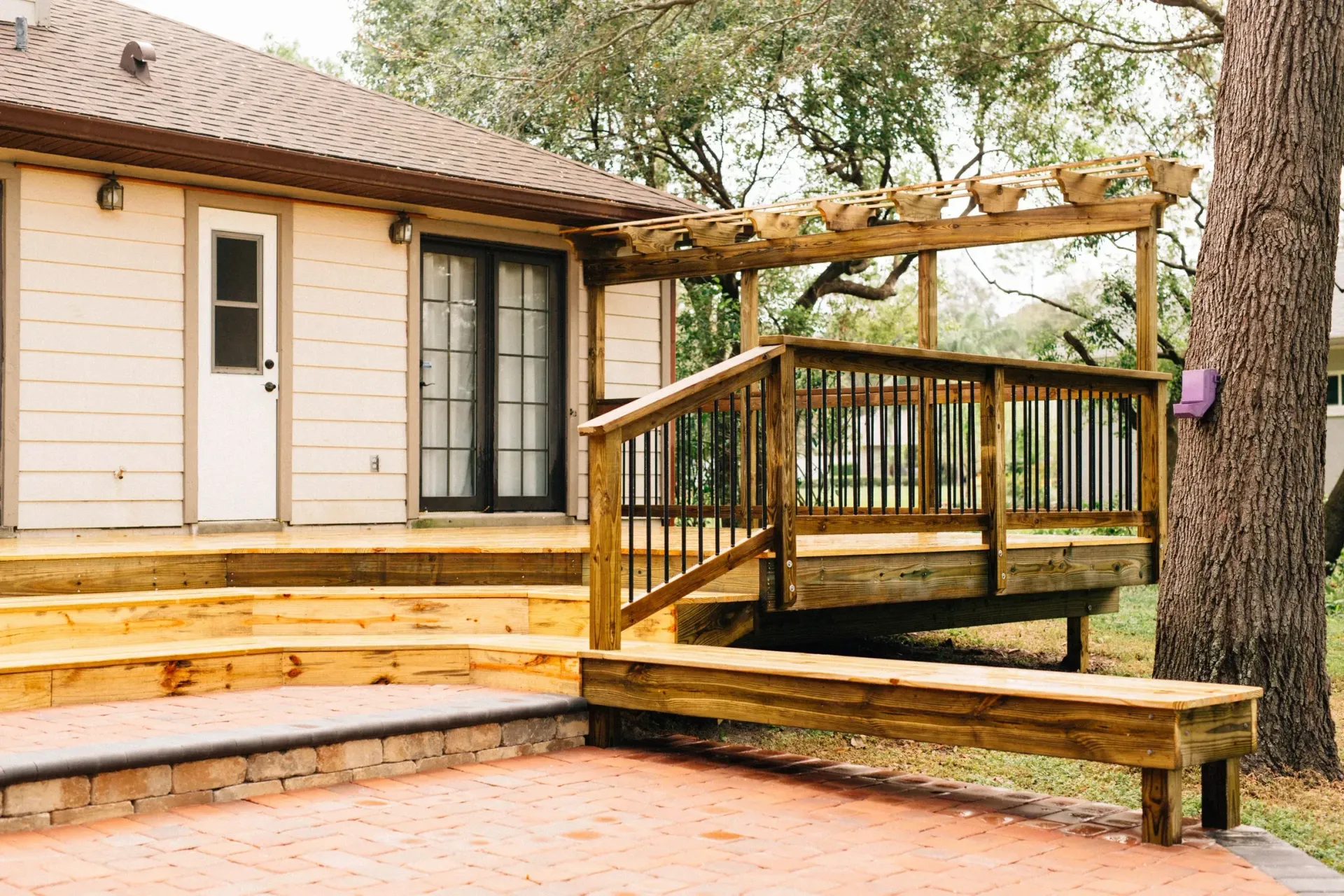 A wooden deck with stairs and a bench in front of a house.