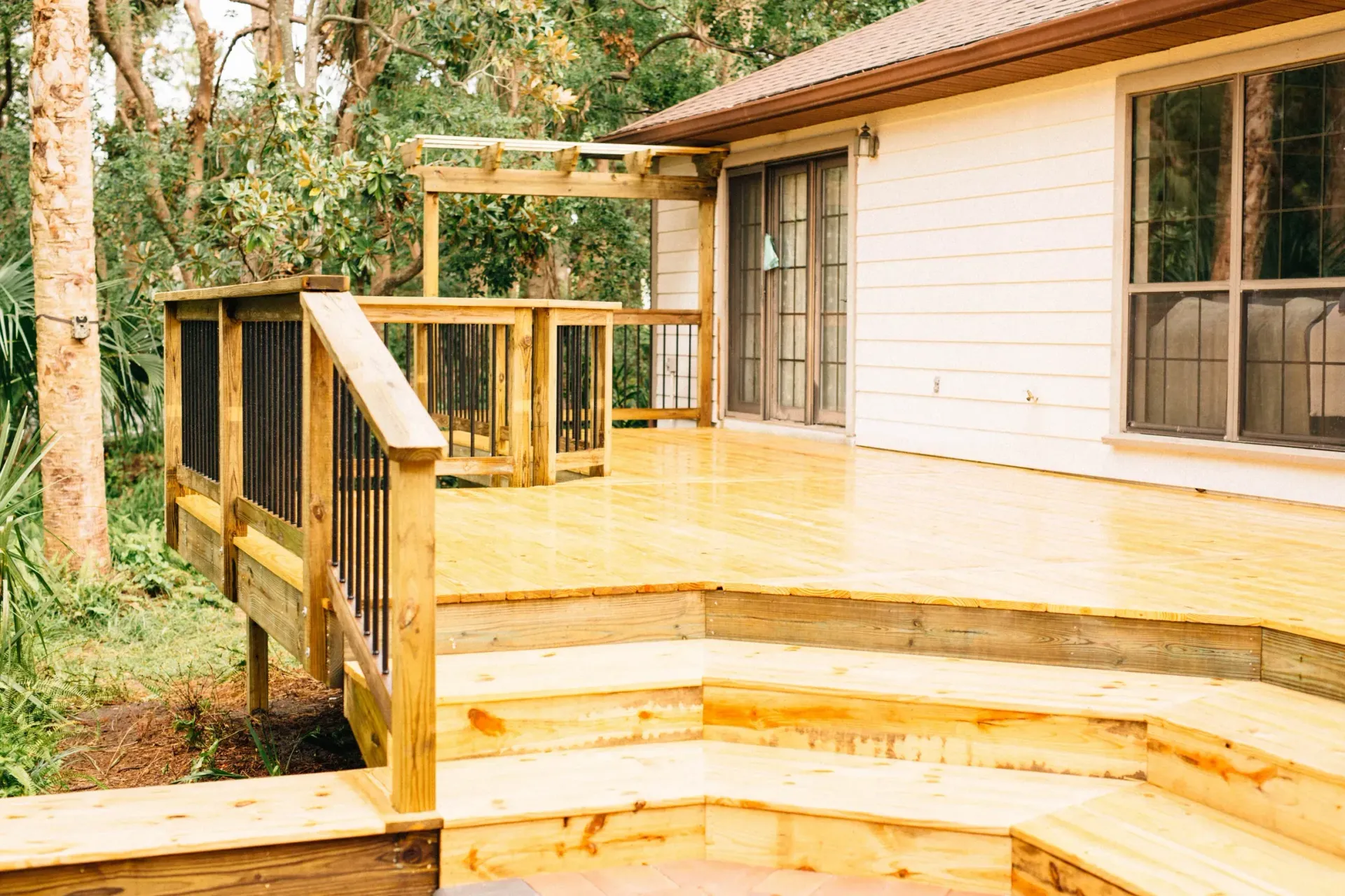 A wooden deck is sitting in front of a white house.