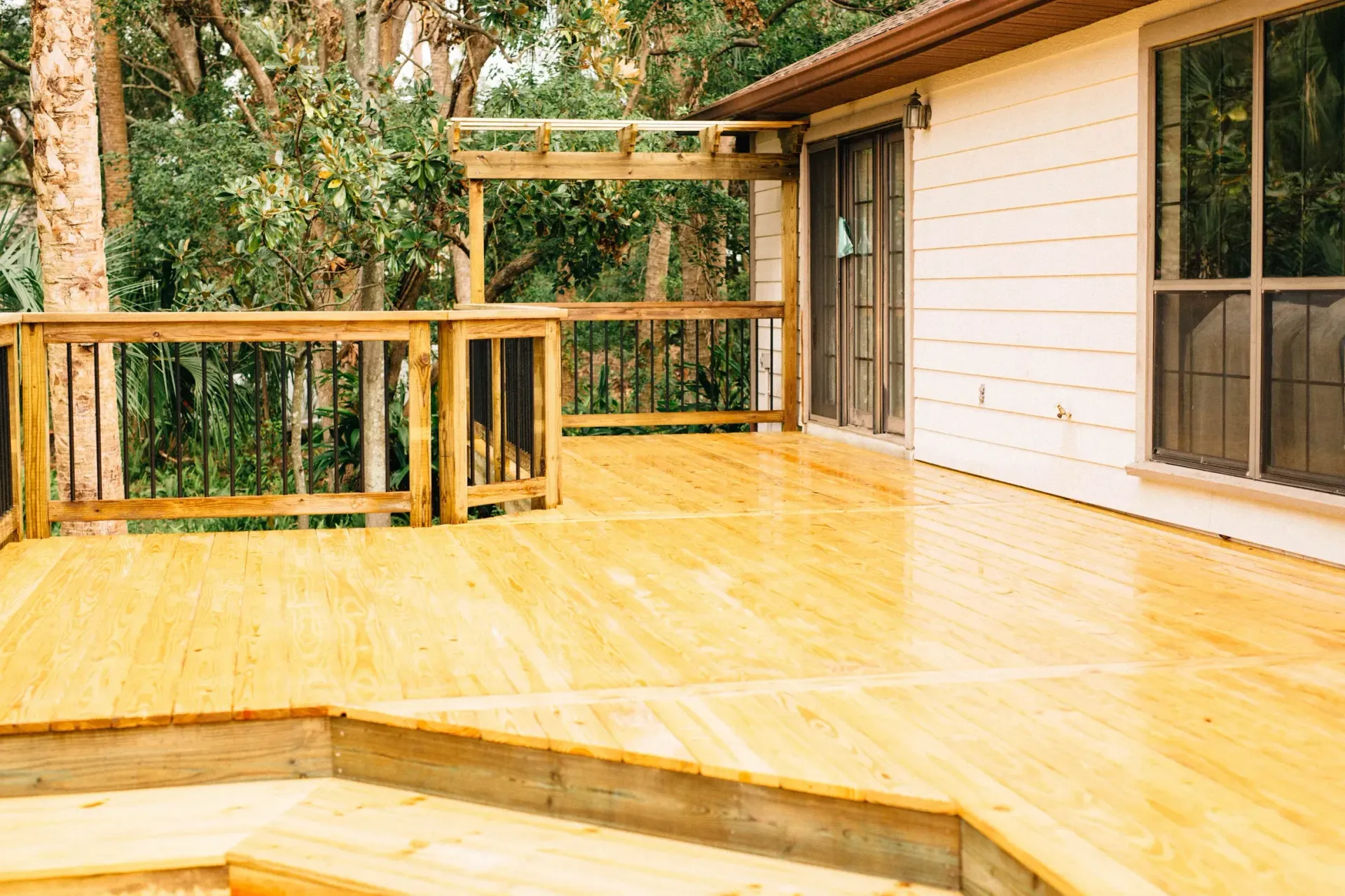 A wooden deck is sitting in front of a white house.