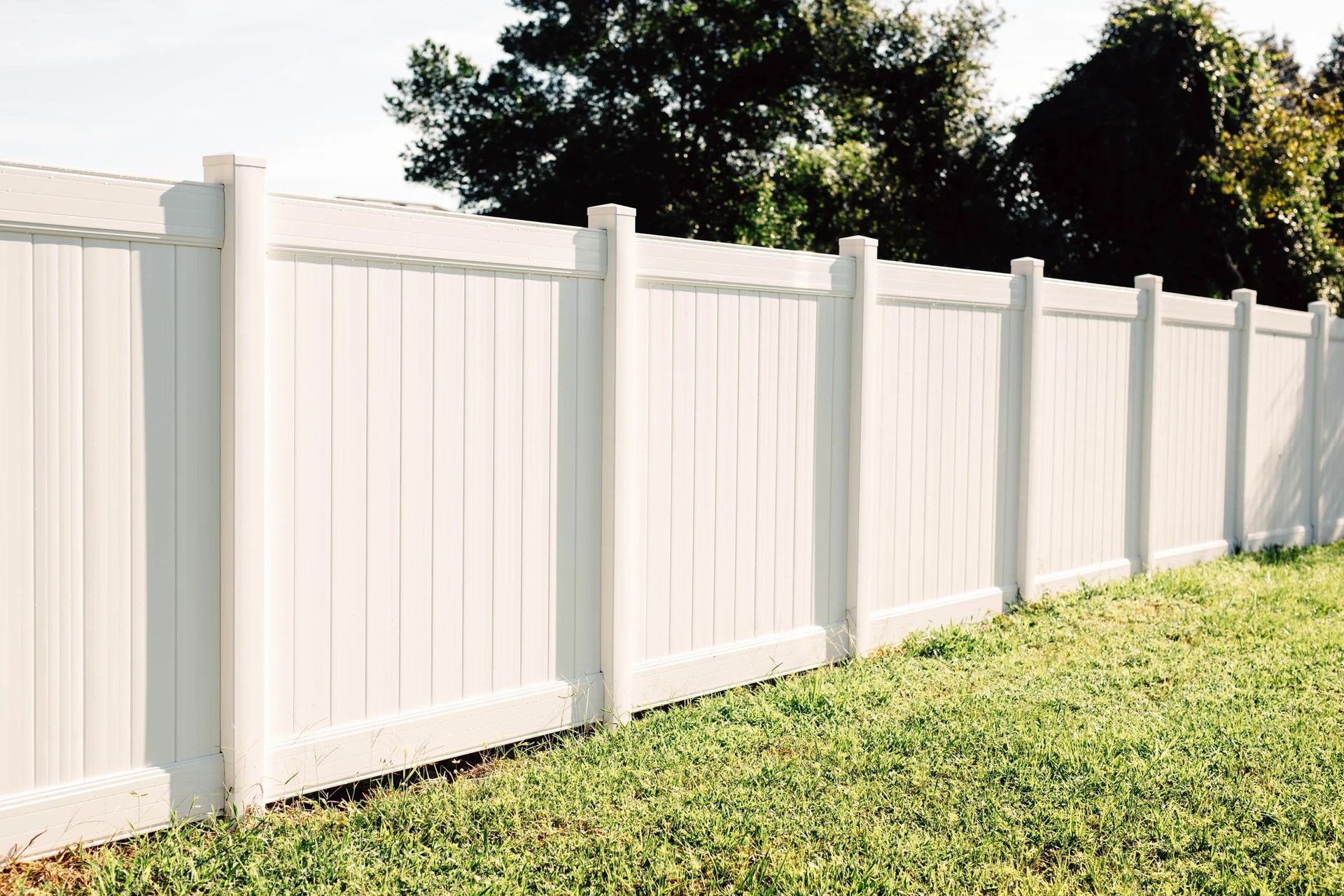 A white fence is sitting in the middle of a lush green field.