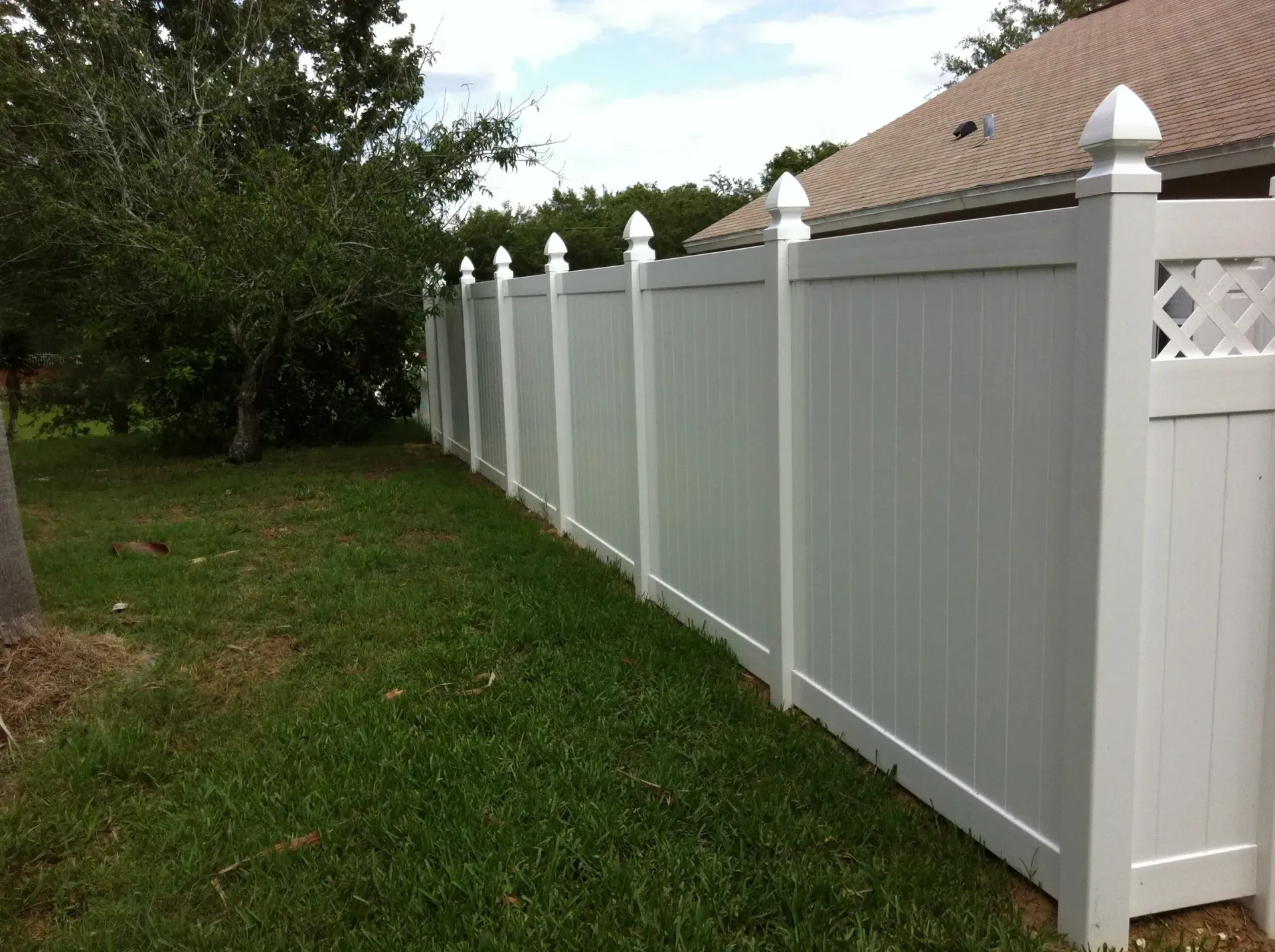 A white fence is sitting in the grass in front of a house.