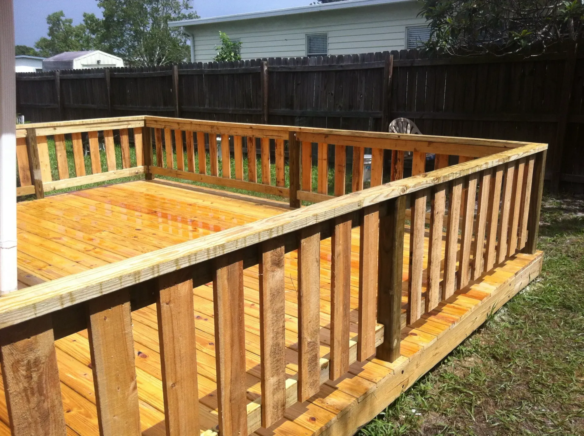 A wooden deck with a fence around it in a backyard.