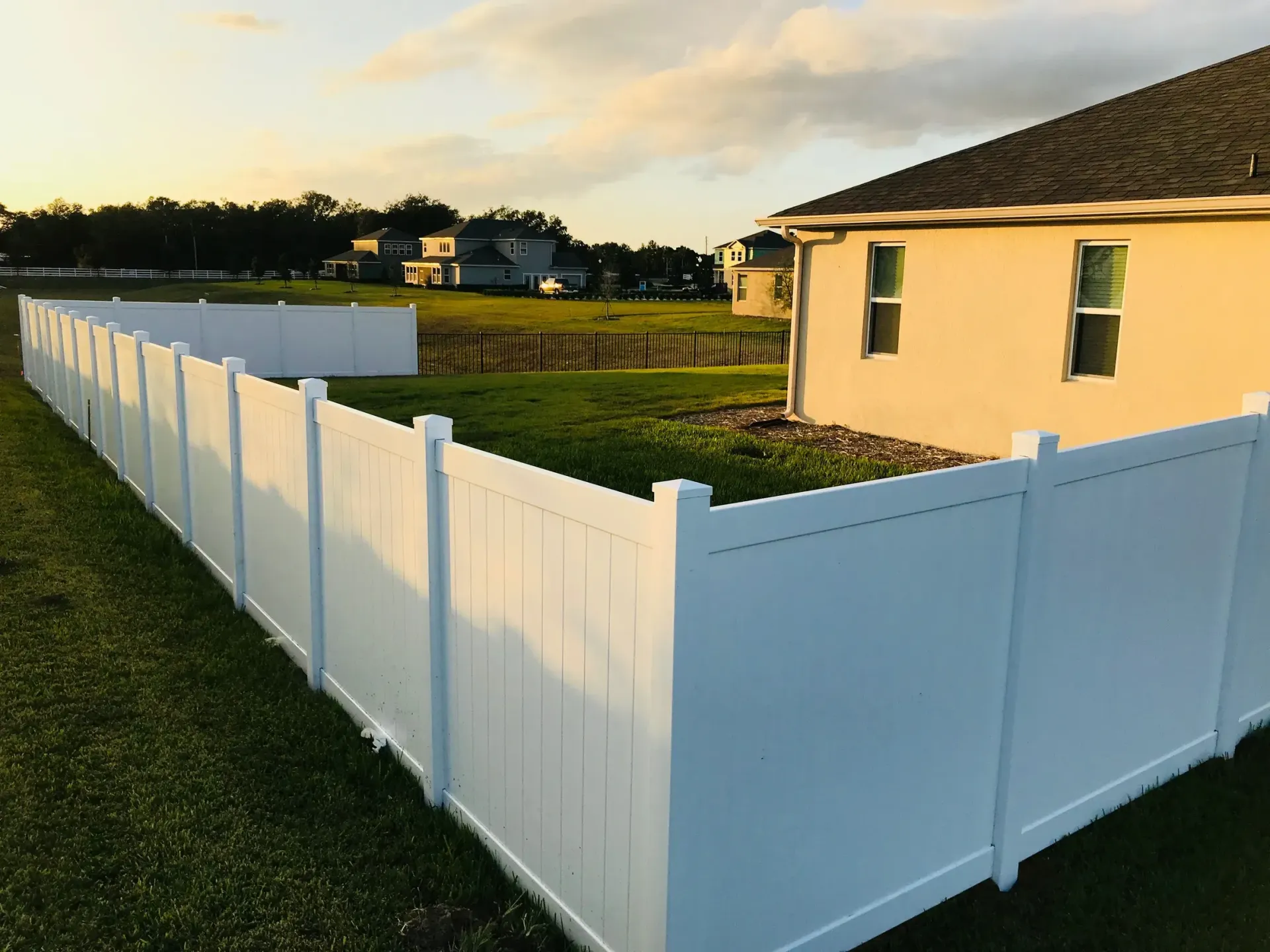 A white fence surrounds a house in a residential area.