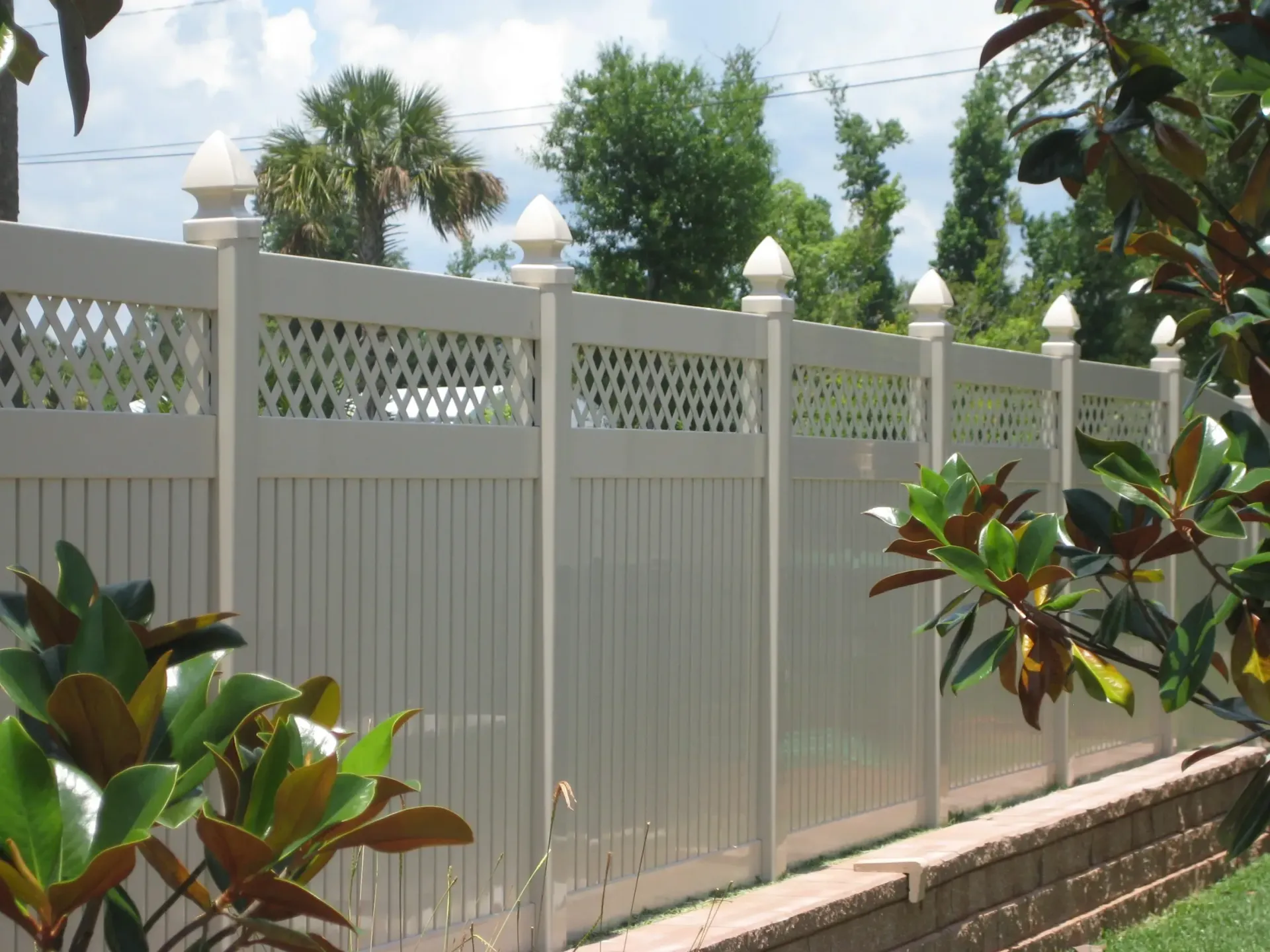 A white fence with a brick wall behind it