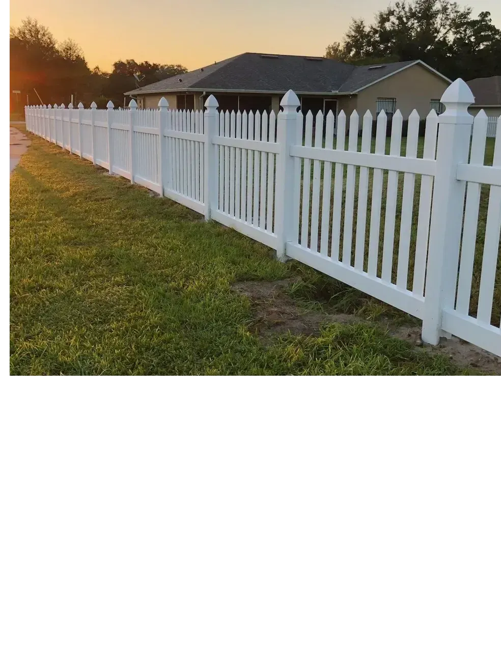A white picket fence is in front of a house.