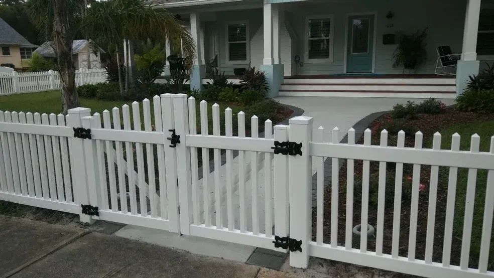 A white picket fence is in front of a house.