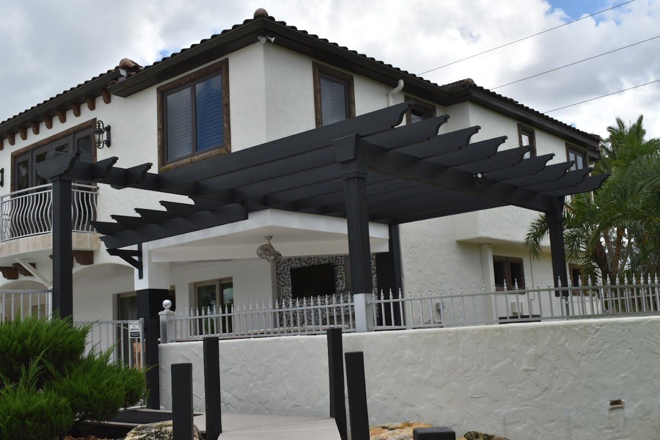 A white house with a black pergola in front of it