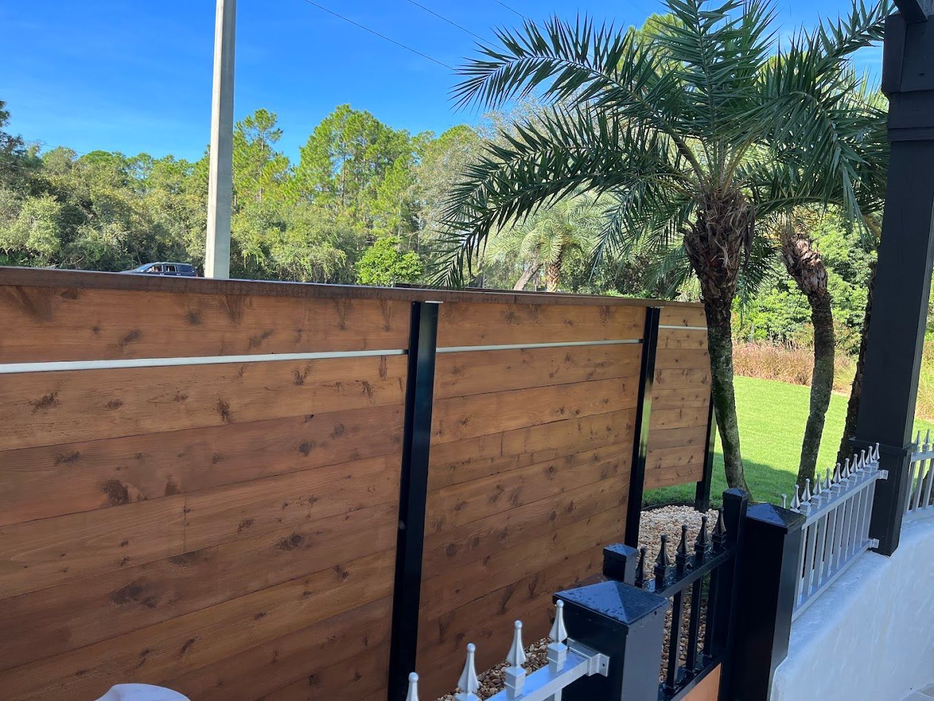 A wooden fence with a palm tree in the background.