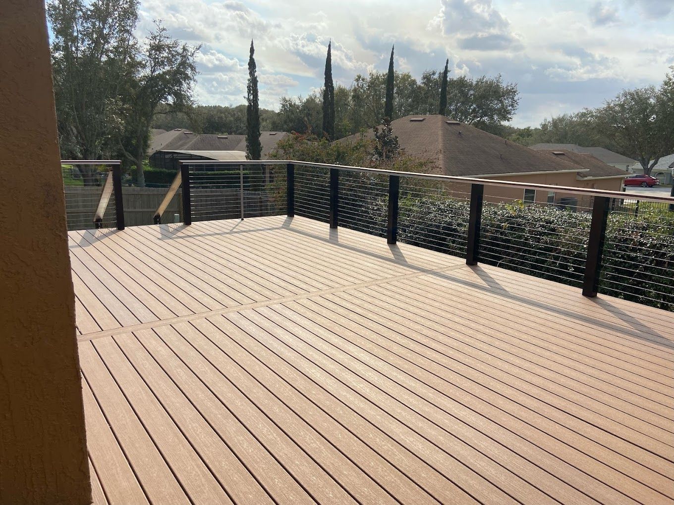 A wooden deck with a metal railing and trees in the background.