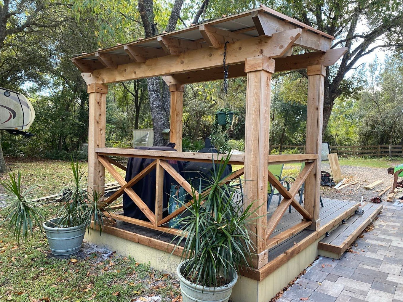 A wooden gazebo is being built in a backyard.