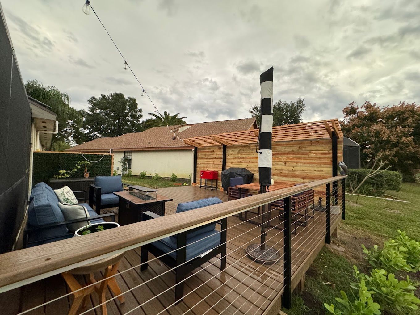 A wooden deck with a lot of furniture on it and a house in the background.