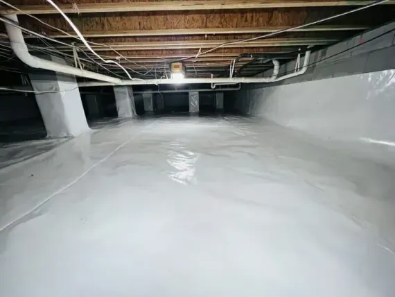 Unfinished basement with white floor coating, exposed ceiling beams, and gray walls