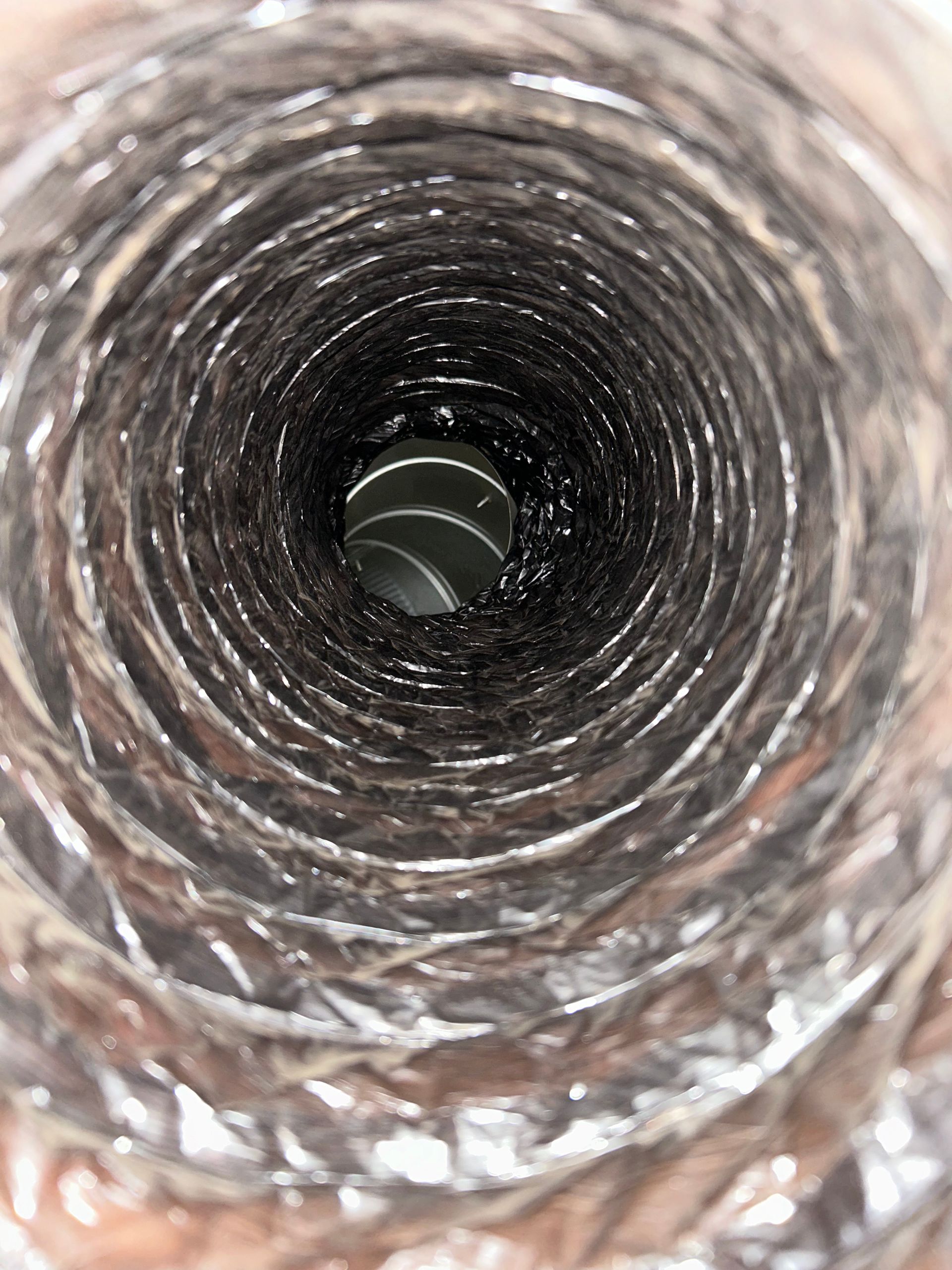 Inside a narrow reflective metal pipe, looking down the hollow center