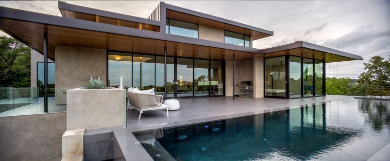 A modern house with a large swimming pool in front of it.