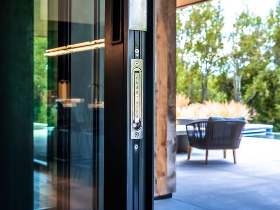 A sliding glass door is open to a patio with chairs and a table.