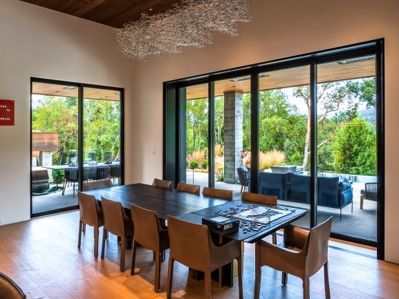 A large dining room with a table and chairs and lots of windows.