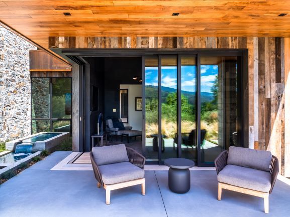 A patio with chairs and a table in front of a sliding glass door.