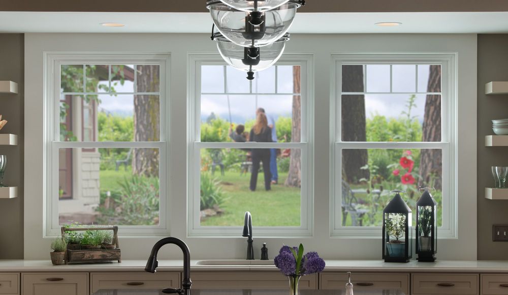 A kitchen with a sink , two windows and a chandelier.