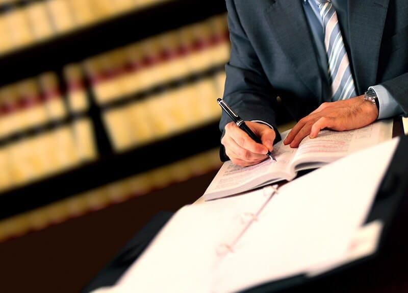 Un hombre con traje y corbata está escribiendo en un cuaderno