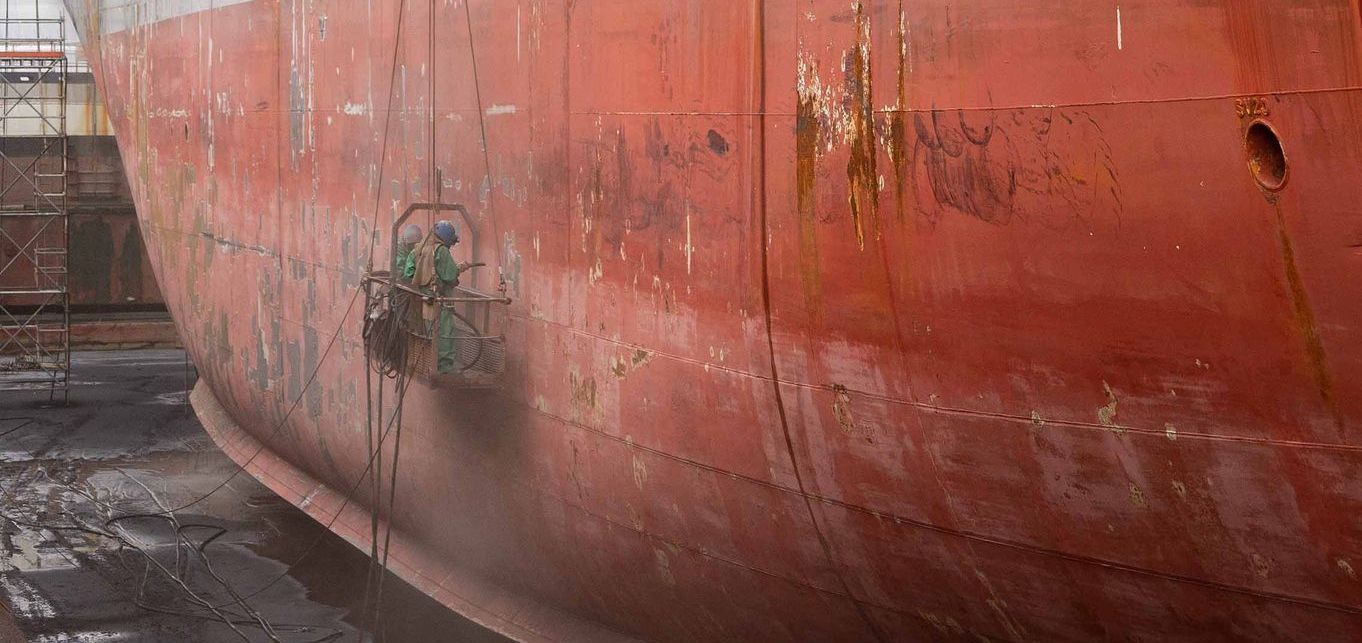 A large red ship is sitting in a dock.