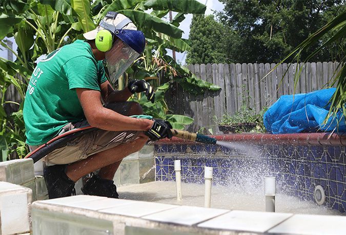 A man is sandblasting tile on a pool