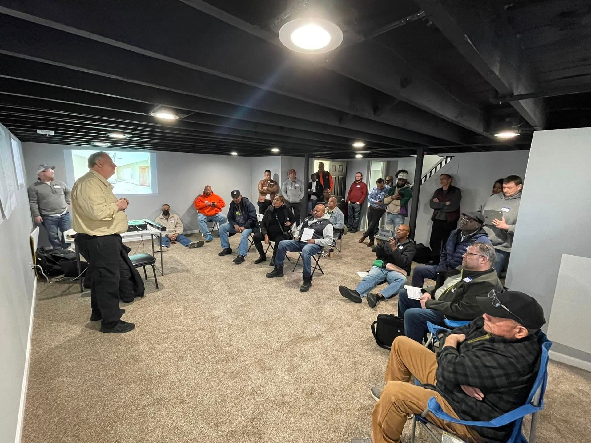A man is giving a presentation to a group of people sitting in chairs in a room.