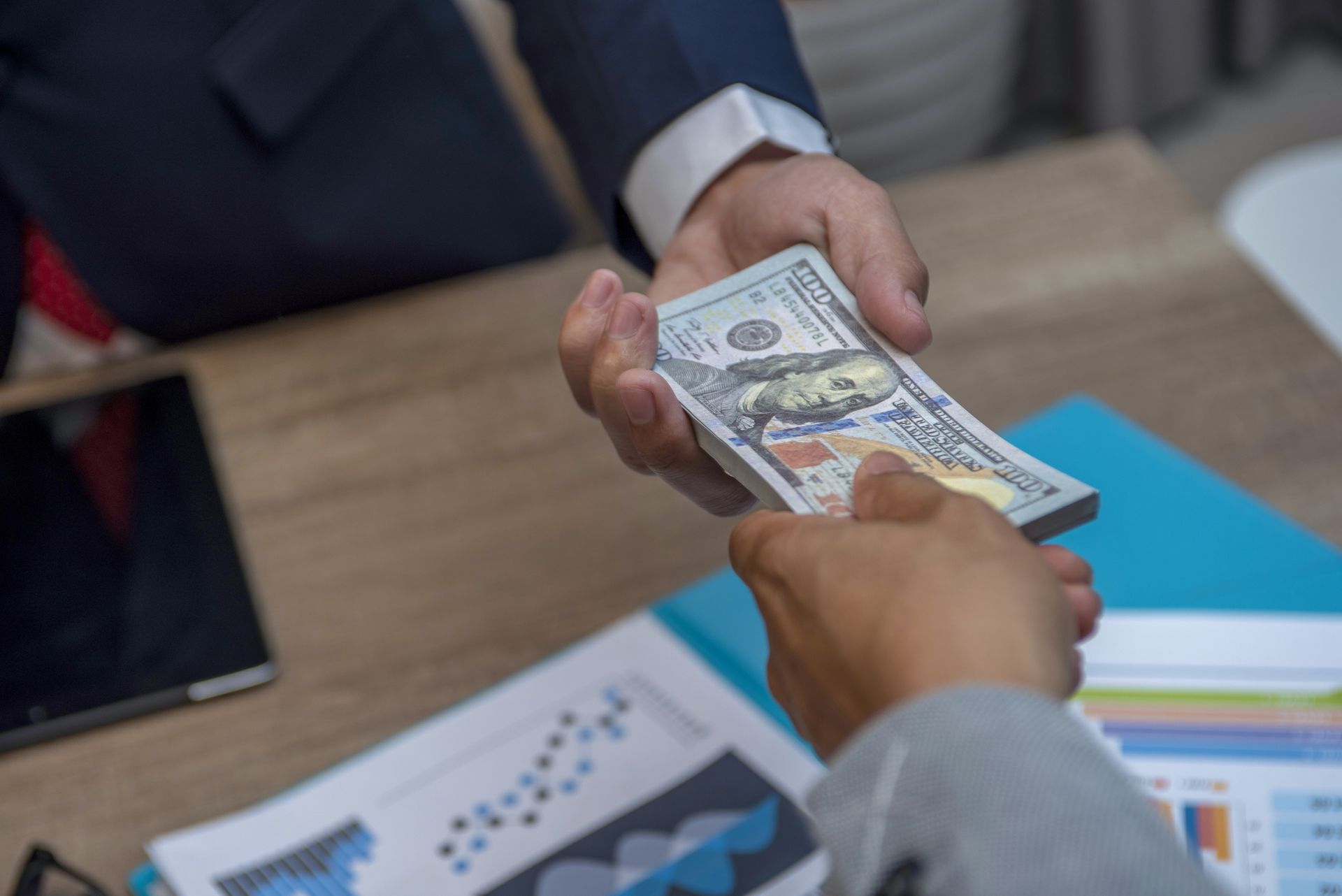 A man is handing a woman a stack of money.