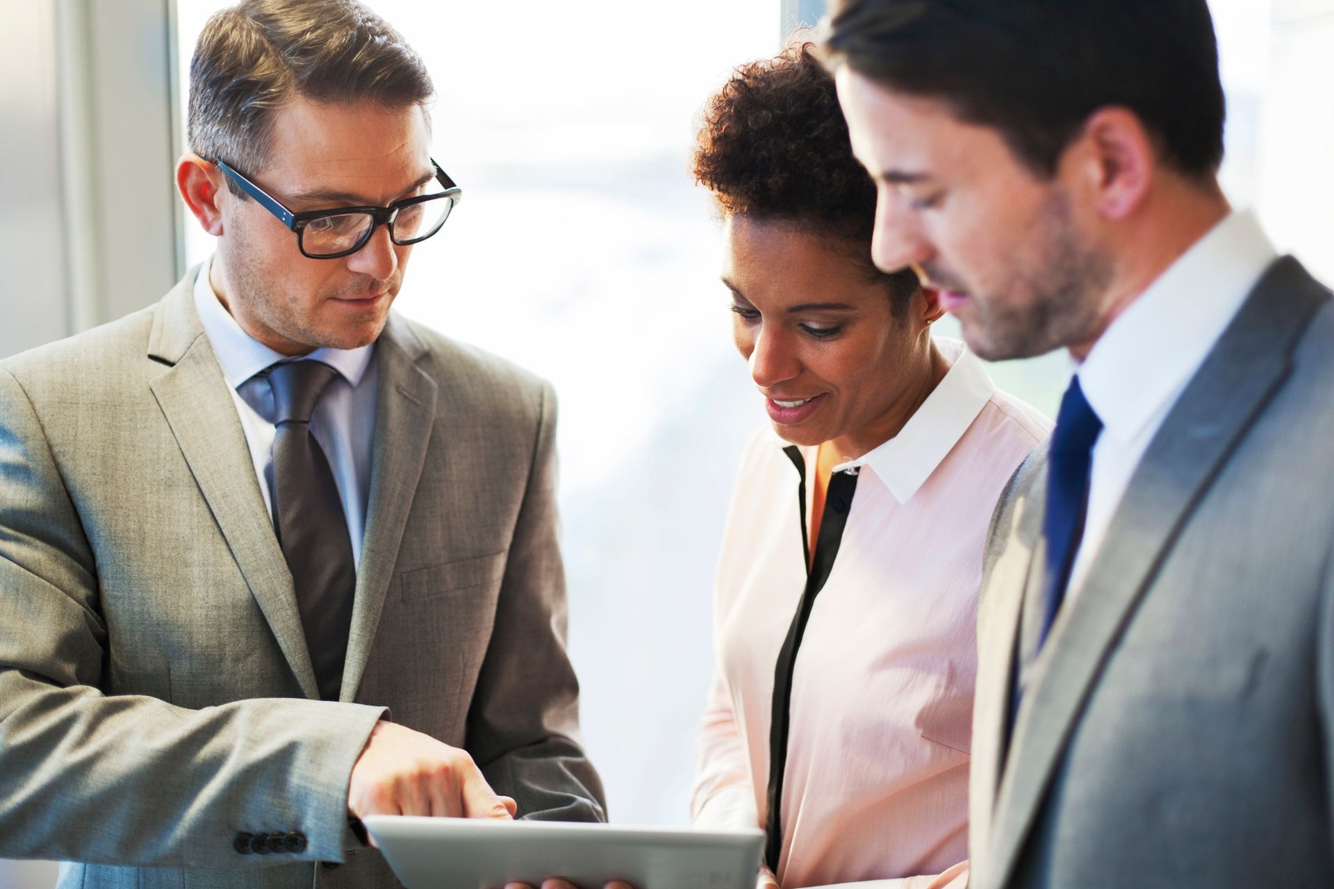 A group of business people are looking at a tablet computer.