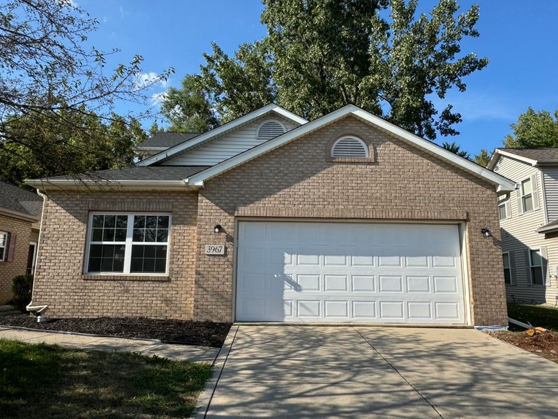 The front of a brick house with a white garage door.